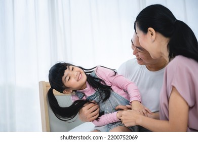 Cheerful Young Asian Family Of Handsome Father And Beautiful Mother Lying On Bed With Cute Little Daughter Laughing While Watching A Comedy Movie On Laptop And Relaxing At Home