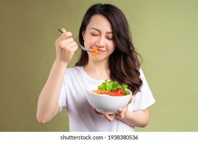 Cheerful young asian girl eating health food on background