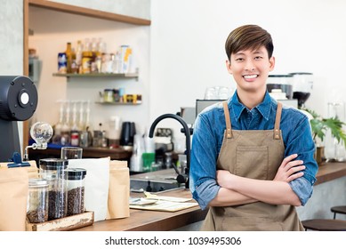 Cheerful Young Asian Man Entrepreneur Standing At Counter In His Own Coffee Shop