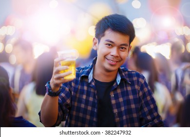 Cheerful Young Asian Man Holding Glass Of Beer In The Big Party