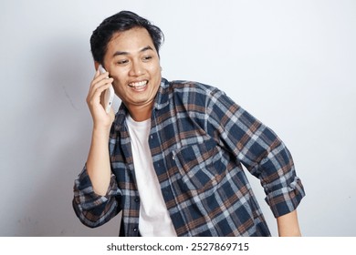 Cheerful young Asian man in plaid shirt talking on mobile phone isolated on white background - Powered by Shutterstock