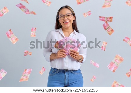 Cheerful young Asian woman holding money banknotes isolated over white background