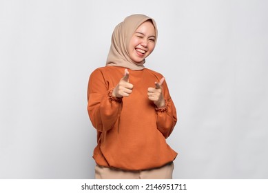 Cheerful Young Asian Woman In Orange Shirt Pointing Fingers At Camera Isolated Over White Background