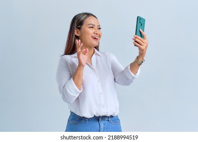 Cheerful Young Asian Woman Saying Hi And Waving Hand While Making Video Call On Mobile Phone Isolated Over White Background