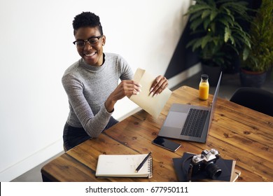 Cheerful Young Attractive Afro American Freelancer Opening Envelope With Business Plan Of Successful Project, Happy Female Black Model Holding Envelope With Copy Space For Advertising Receiving Letter