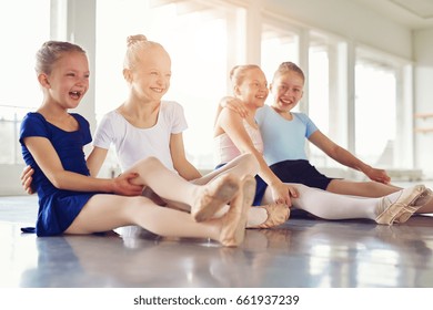 Cheerful young ballerinas smiling and embracing sitting on floor in ballet class together. - Powered by Shutterstock