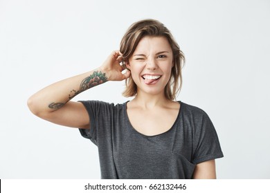 Cheerful young beautiful girl smiling winking showing tongue looking at camera over white background.