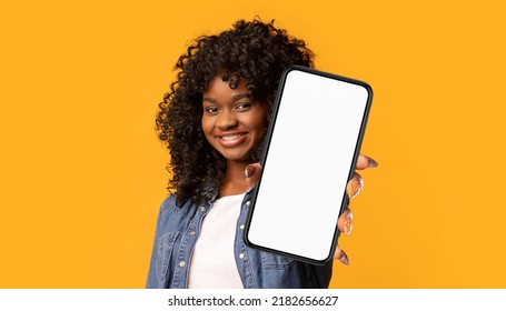 Cheerful young black woman showing modern cell phone with white empty screen on yellow studio background, panorama, copy space. Positive african american pretty lady recommending mobile app, collage - Shutterstock ID 2182656627
