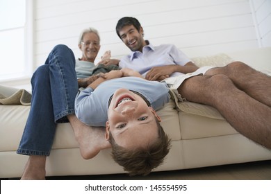 Cheerful Young Boy Having Fun With Father And Grandfather On Sofa