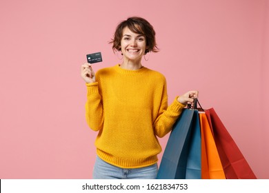 Cheerful young brunette woman girl in yellow sweater posing isolated on pink background. People lifestyle concept. Mock up copy space. Hold package bag with purchases after shopping, credit bank card - Shutterstock ID 1621834753