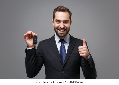 Cheerful Young Business Man In Classic Black Suit Shirt Tie Posing Isolated On Grey Wall Background. Achievement Career Wealth Business Concept. Mock Up Copy Space. Holding Car Keys, Showing Thumb Up