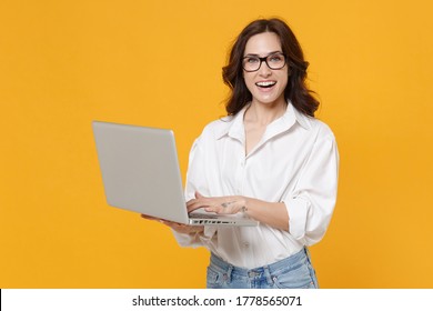 Cheerful Young Business Woman In White Shirt Glasses Isolated On Yellow Wall Background Studio Portrait. Achievement Career Wealth Business Concept. Mock Up Copy Space. Working On Laptop Pc Computer