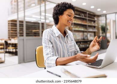 Cheerful Young Businesswoman Having A Video Call In A Warehouse. Online Store Owner Having A Virtual Meeting With Her Dropshipping Partners. Female Entrepreneur Running An E-commerce Small Business.