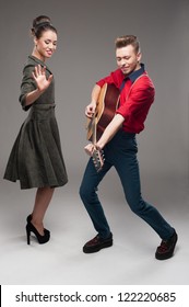 Cheerful Young Caucasian Guitar Player And Dancing Girl In Vintage Clothing Over Gray Background