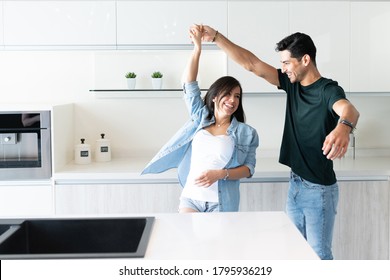 Cheerful Young Couple Dancing By Kitchen Island At Home