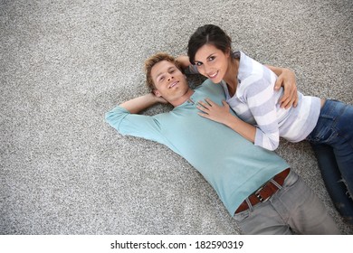 Cheerful Young Couple Laying On Carpet Floor