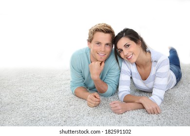 Cheerful Young Couple Laying On Carpet Floor