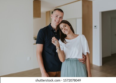 Cheerful Young Couple In New House Holding Keys