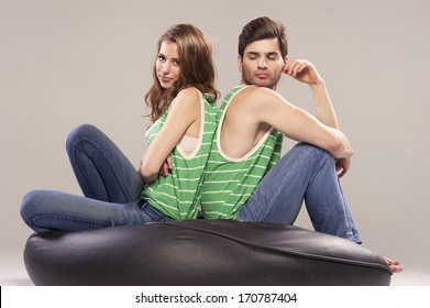 Cheerful Young Couple Sitting With Back To Each Other On Floor, Weird Faces