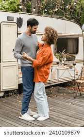 Cheerful young couple spouses girlfriend and boyfriend dancing together, spending time on a date while traveling by camper van caravanning by trailer motor home