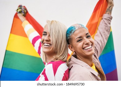 Cheerful young couple of women with rainbow flag at gay pride event - Focus on face - Shutterstock ID 1849695730