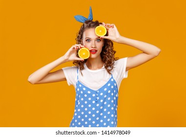 cheerful young curly woman girl with   orange   on a yellow color background - Shutterstock ID 1414978049