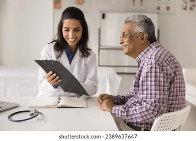 Cheerful young doctor woman showing medical report to elderly patient man, explaining healthcare examination results, prescription, treatment recommendation, giving consultation - Powered by Shutterstock