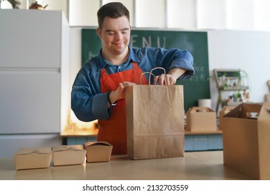 Cheerful young Down Syndrome waiter working in take away restaurant, social inclusion concept. - Powered by Shutterstock