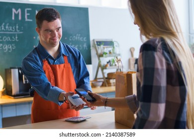 Cheerful young Down Syndrome waiter taking contactless smartphone payment from costumer in take away restaurant. - Powered by Shutterstock