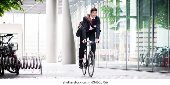 Cheerful Young Employee With A Healthy Lifestyle Riding An Utility Bicycle To A Modern Workplace In Berlin