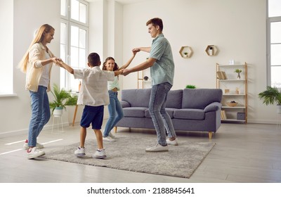 Cheerful young family with two children spend time together playing at home in living room. Mom, dad and little son and daughter dance while walking in circle holding hands. Family concept. - Powered by Shutterstock