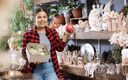 Cheerful Young Female In Casual Shirt Buying Christmas Bulbs Before Holidays In A Store
