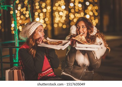 Cheerful Young Female Friends Are Seating Slices Of Pizza And Having Fun At Holiday Winter Night In The City Street.