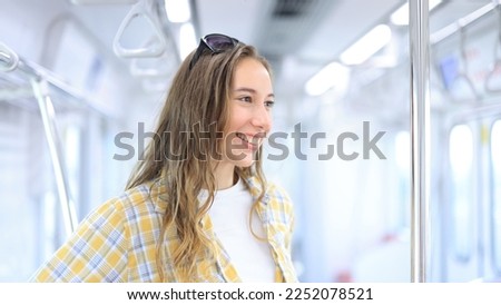 Cheerful young female traveling, sitting ing in MRT train. Enjoying travel. Caucasian traveler woman traveling by Mass Rapid Transit(MRT) train using tablet, smartphone. Transportation, travel concept