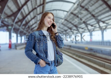 Cheerful young female travelling, standing in train station. Enjoying travel. Caucasian traveller woman traveling 