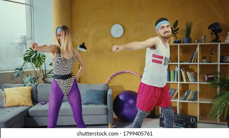 Cheerful Young Fitness Couple Stretching Their Muscles Together. Retro Style Man And Woman From 80s Doing Home Exercises Warm-up Training. Pair Workout. Fun Concept.