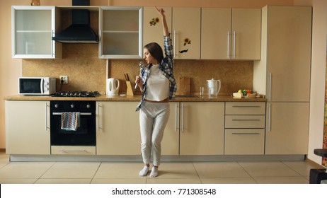 Cheerful Young Funny Woman Dancing And Singing With Ladle While Having Leisure Time In The Kitchen At Home