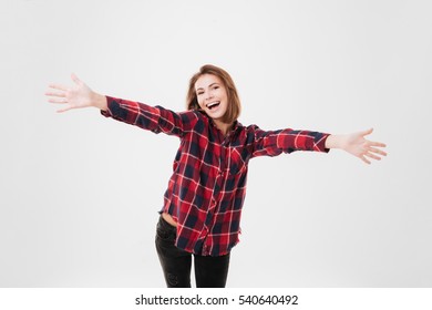 Cheerful young girl in plaid shirt greeting you over white background