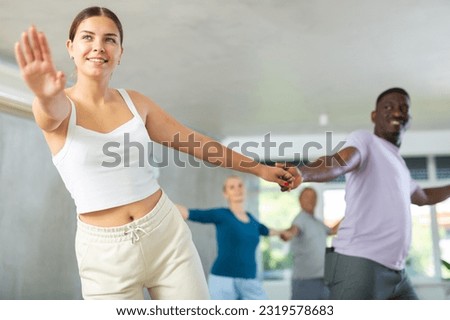 Cheerful young girl practicing vigorous boogie-woogie moves with african american male partner in dance class. Social dancing concept