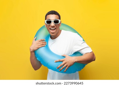 cheerful young guy afro american in sunglasses with inflatable swimming ring on yellow isolated background, man in summer on beach, concept of travel and summer holidays - Powered by Shutterstock