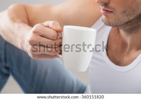 Cheerful young guy is drinking hot tea