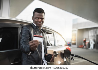 Cheerful Young Handsome Black Man Smiling To Camera And Demonstrating His Credit Card Before Paying For Gasoline On Modern Petrol Station. Cashless Payment Concept