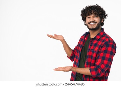 Cheerful young Hindi man in casual attire showing copy space isolated over white background. Handsome Indian boy pointing presenting free space for promotion goods offers - Powered by Shutterstock