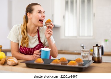 Cheerful young housewife tasting baked muffins at - Powered by Shutterstock