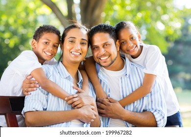 Cheerful Young Indian Family Sitting Together In The Park