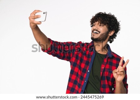 Cheerful young Indian man vlogging blogging on cellphone for social media isolated over white background. Hindi influencer doing taking selfie, having videocall