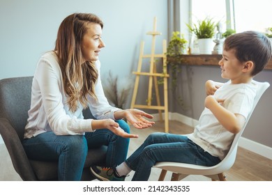 Cheerful young kid talking with helpful child counselor during psychotherapy session in children mental health center. Child counselor during psychotherapy session - Powered by Shutterstock