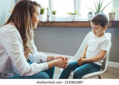 Cheerful Young Kid Talking With Helpful Child Counselor During Psychotherapy Session In Children Mental Health Center. Child Counselor During Psychotherapy Session