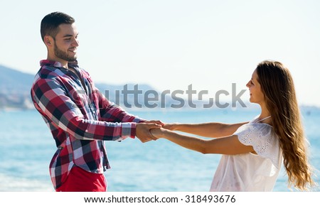 Cheerful young lovers spending time together at sea shore