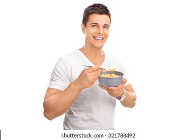 Cheerful Young Man Eating Cereal From A Bowl And Looking At The Camera Isolated On White Background